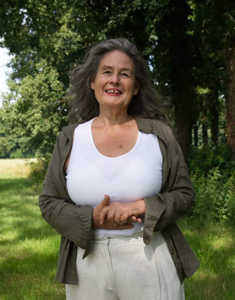 Vrolijke oudere vrouw in een park, glimlachend en ontspannen.