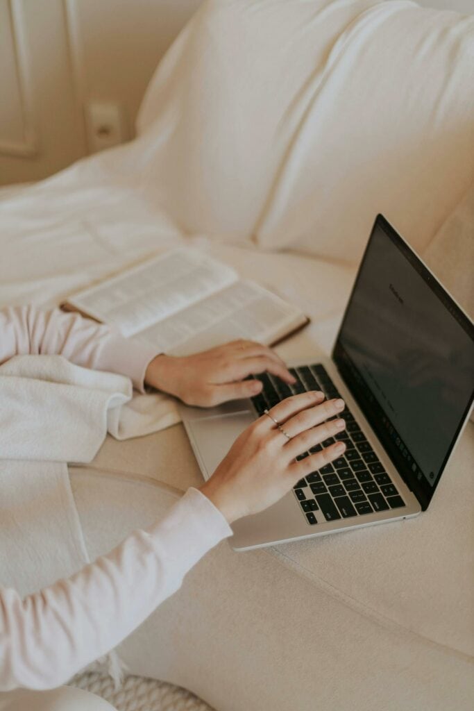 Persoon werkt op laptop op bank, online marketing en SEO optimalisatie.