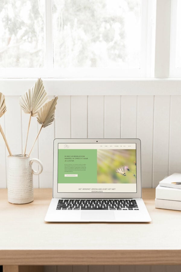 Laptop met Nederlandse begeleidingswebsite op houten bureau